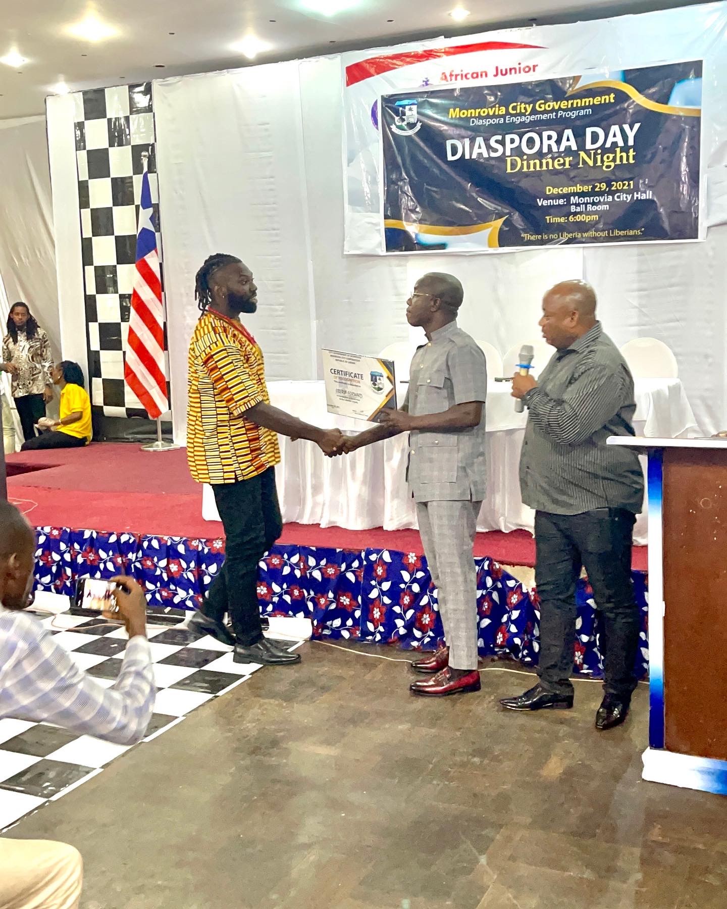 Lawrence receiving the certificate on stage at Diaspora Day Dinner Night, Monrovia City Hall